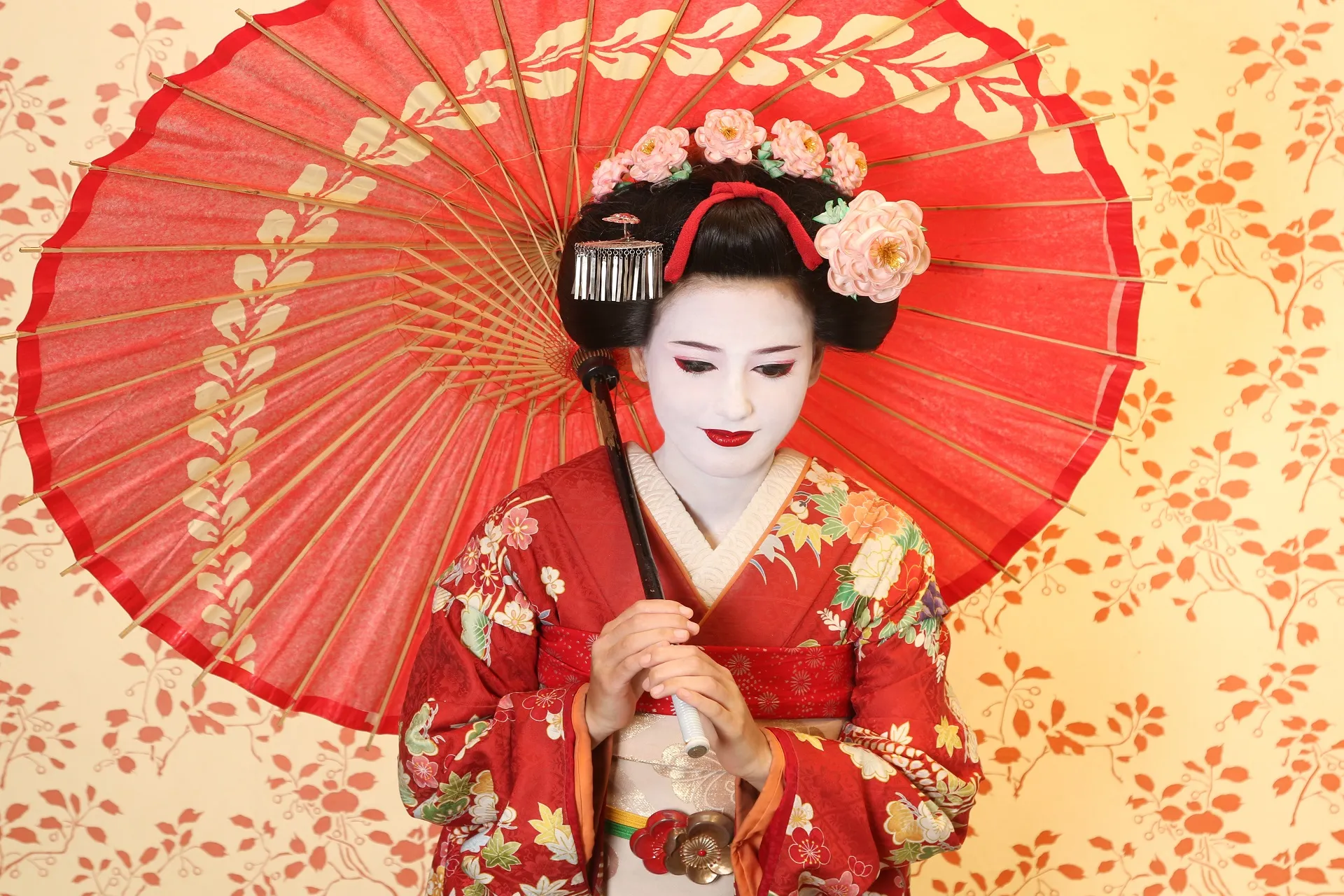 Maiko standing holding a traditional wagasa, showcasing Japanese elegance.